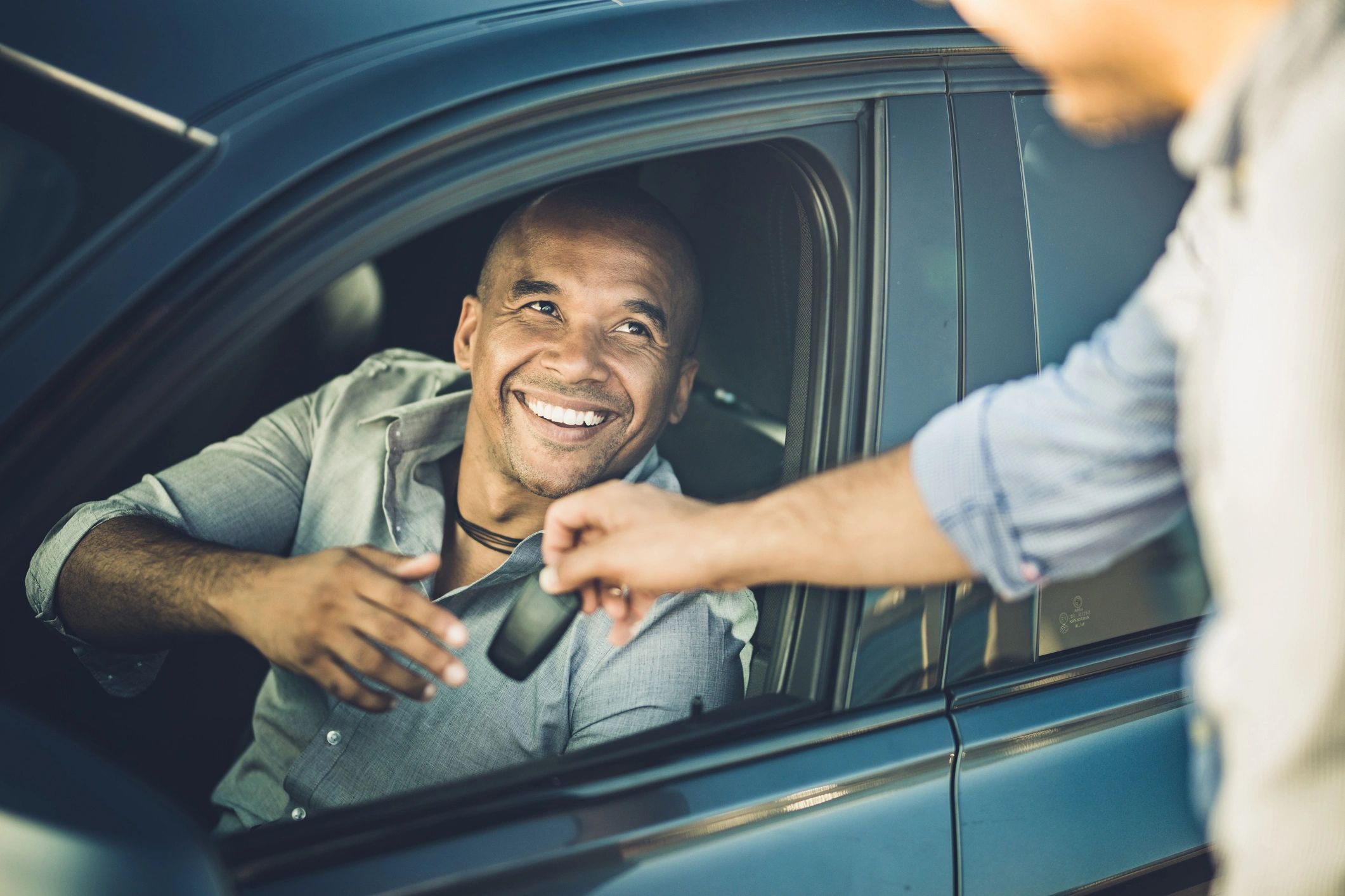 Black customer receiving car keys from a rental agent